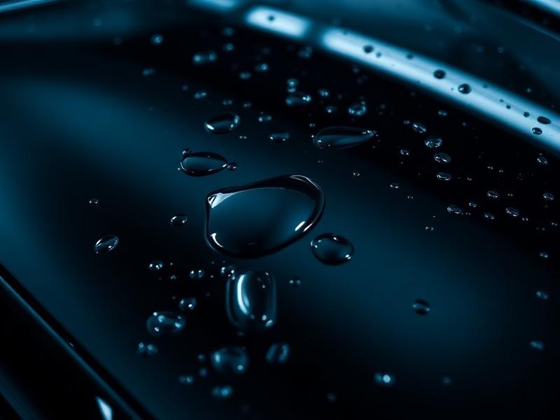 Water beading on a freshly ceramic-coated glossy black car hood